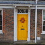 Yellow door in London with red Christmas flowers on it.