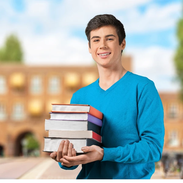 Young guy is holding a bunch of books on the front of the British Schools